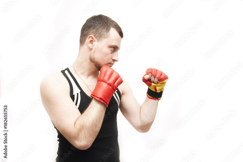 young guy fighter wearing gloves blows against a white background
