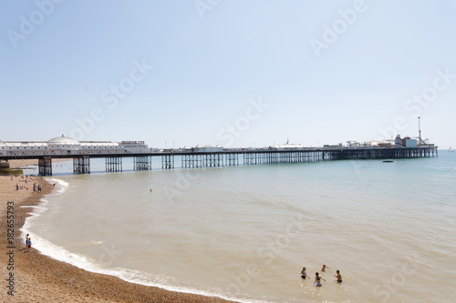 Sunbathing people on the Brighton beach  Brighton pier in the background