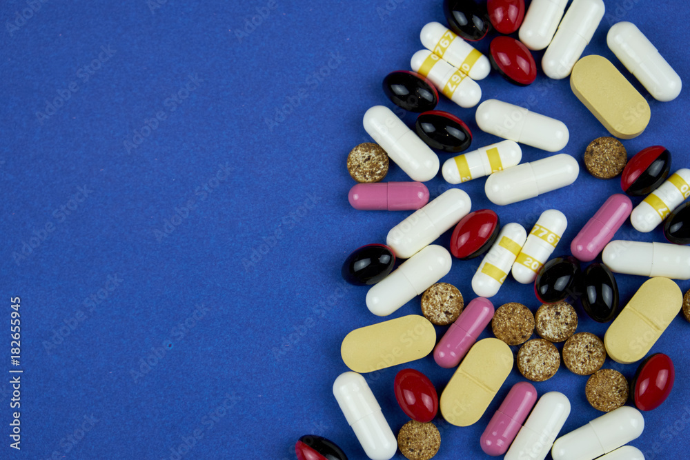 white and yellow pills, tablets, vitamins, medicine, pills and drugs scattered on the blue table. Pills for treatment and medicine. white and yellow pills, tablets, vitamins, medicine, pills and drugs scattered on the blue table. Pills for treatment and medicine.