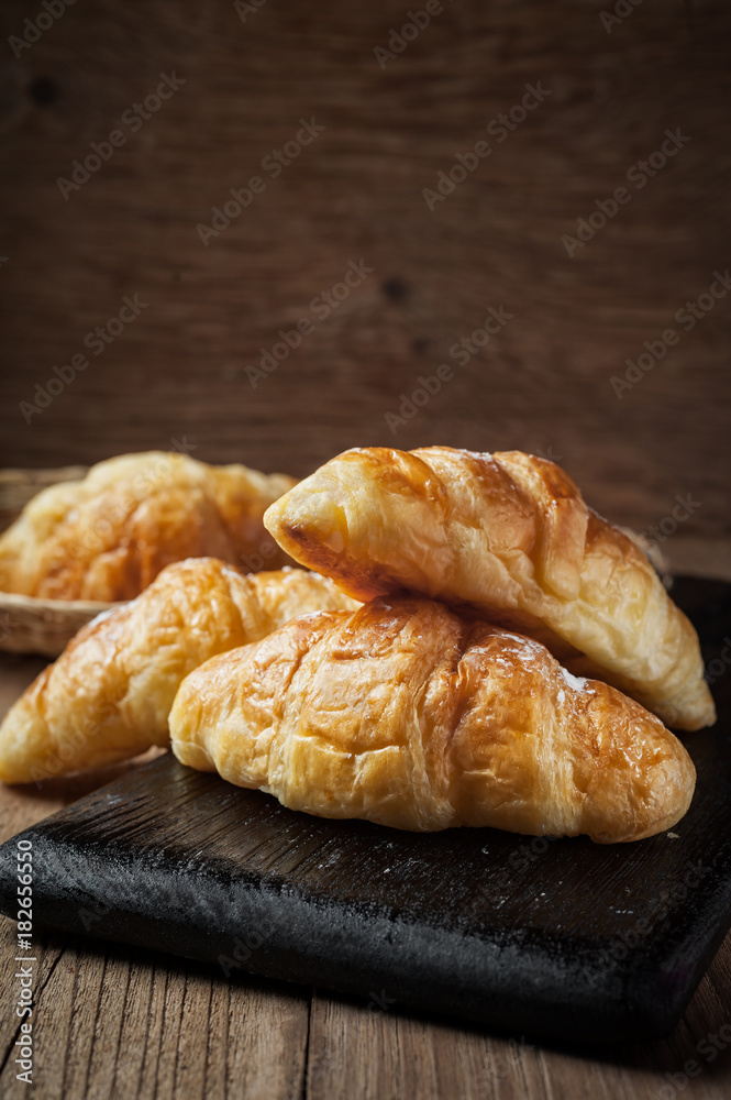 Fresh baked croissant sprinkled with powdered sugar on table