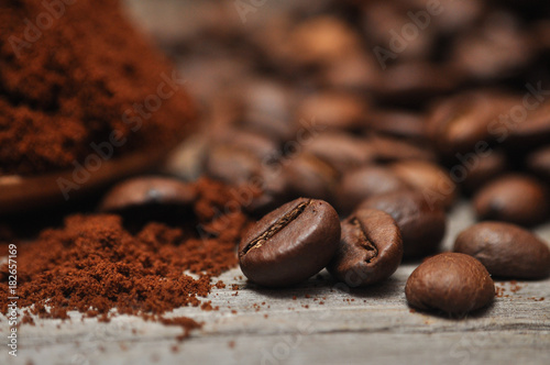 Milled coffee and coffee beans on old wooden background 