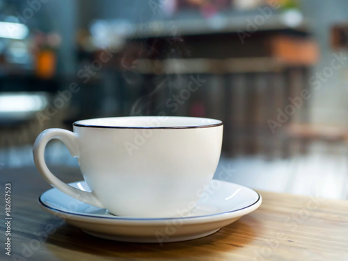 Hot coffee  white cup of espresso on wood table with blur background of sunlight in cafe or coffeeshop.