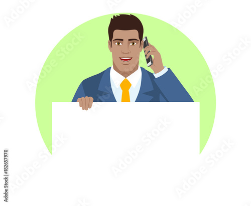 Businessman holding white blank poster and talking on the mobile phone