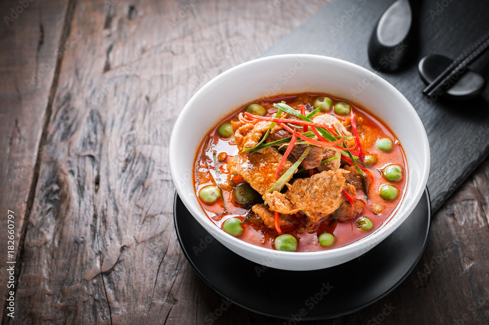 Red curry with pork and coconut milk, delicious Thai food on wooden table. Red curry with pork and coconut milk, delicious Thai food on wooden table.