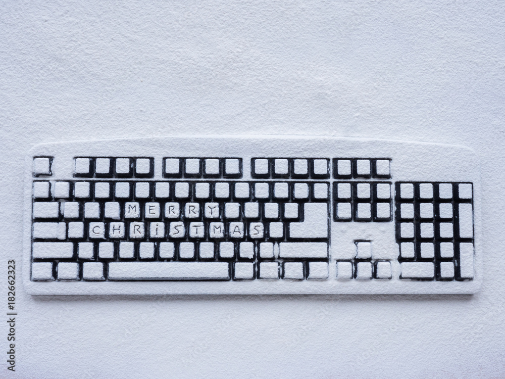 wireless computer keyboard covered with white snow with text merry christmas on buttons