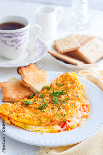 Breakfast with an omelette with tomatoes and cheese, tea and biscuits, selective focus
