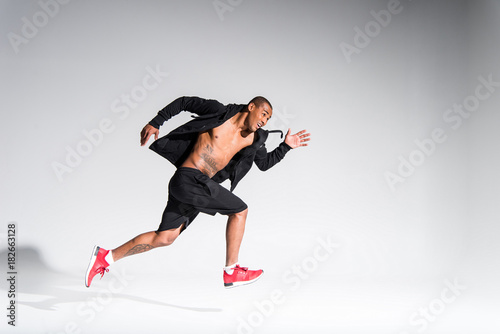 young african american sportsman running on grey