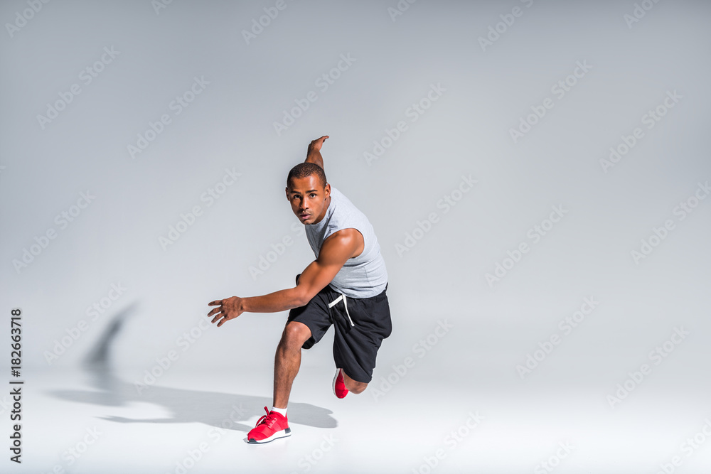 young african american sportsman running and looking at camera on grey - obrazy, fototapety, plakaty 
