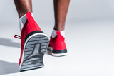 selective focus of african american sportsman in sneakers on grey