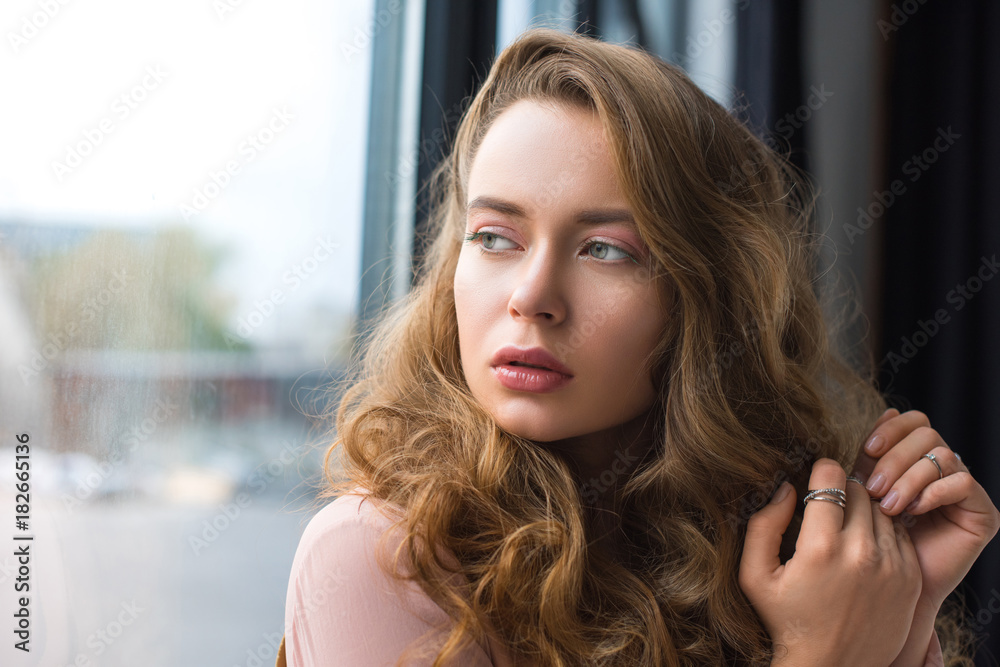 attractive girl with curly hair looking at the window attractive girl with curly hair looking at the window
