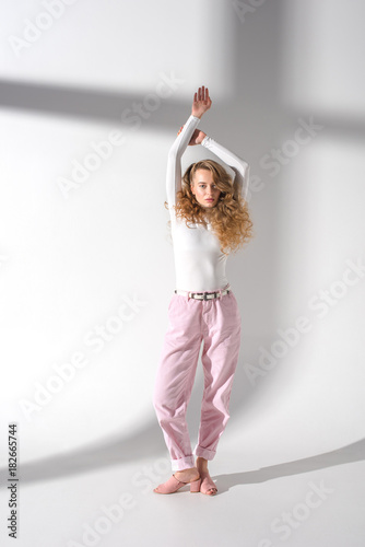 attractive girl with curly hair standing with hands up and looking at camera