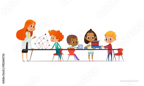 Redhead female teacher and school children standing and sitting around table, building and programming robotic car during engineering lesson. Vector illustration for banner, poster, advertisement.