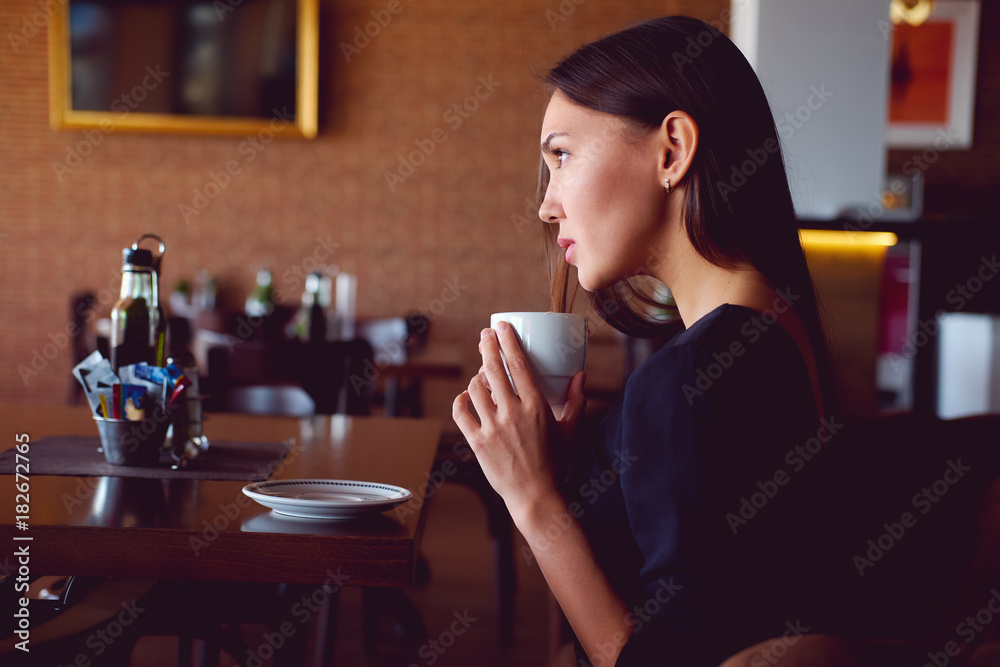 Young brunette with a coffee cup in a restaurant Young brunette with a coffee cup in a restaurant