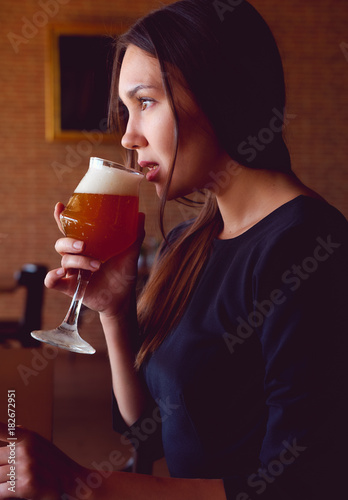 Young brunette drinking a beer in a restaurant