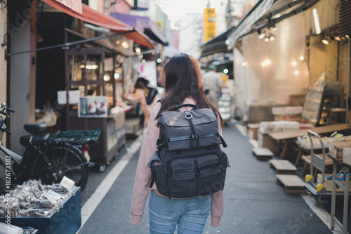 Back side of Asian woman with backpack travelling in market shopping landmark in old city on holiday