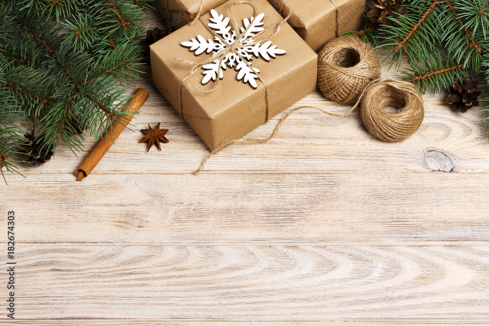 Christmas background with gift boxes wrapped in kraft paper, fir tree branches, pine cones, cinnamon and star anise on white wooden background. Flat lay, top view Christmas background with gift boxes wrapped in kraft paper, fir tree branches, pine cones, cinnamon and star anise on white wooden background. Flat lay, top view