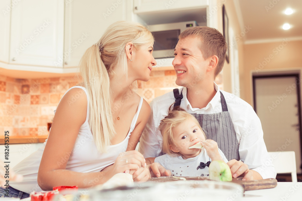 Parents and their two beautiful and cute children girls eating breakfast ot lunch at kitchen table at home Parents and their two beautiful and cute children girls eating breakfast ot lunch at kitchen table at home