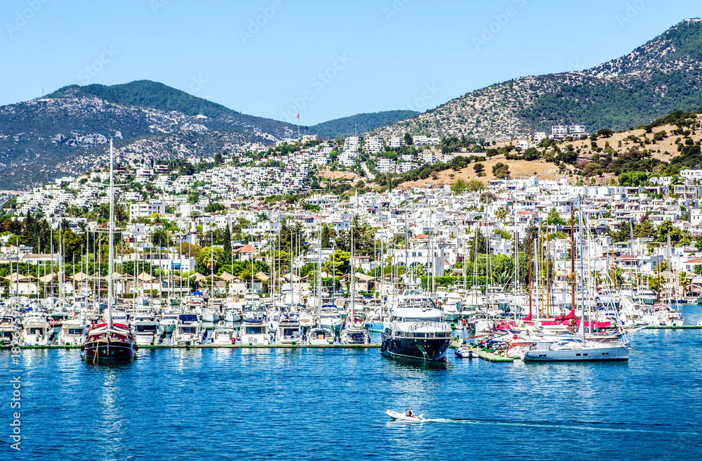 Many yachts moored in the bay of Bodrum against the background of the city and mountains.