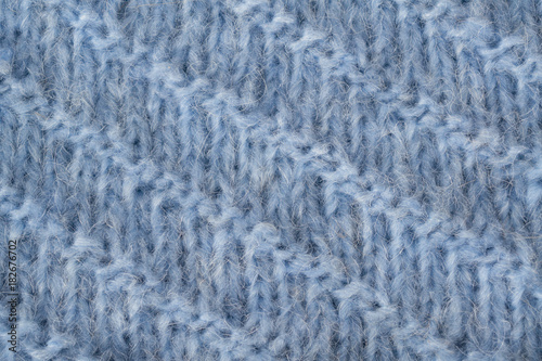 Blue knitted fluffy fabric texture. Hand knitting. Detailed warm yarn background.