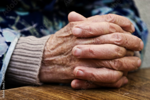 The old grandmother put wrinkled hands on a wooden table