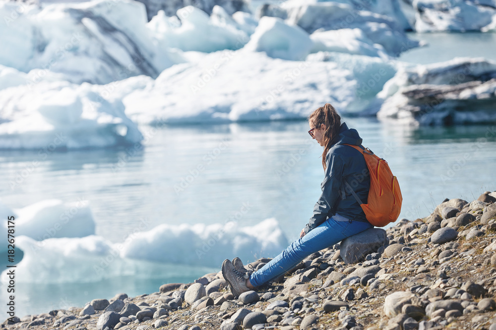 Woman with backpack in Ice Lagoon in Iceland Woman with backpack in Ice Lagoon in Iceland