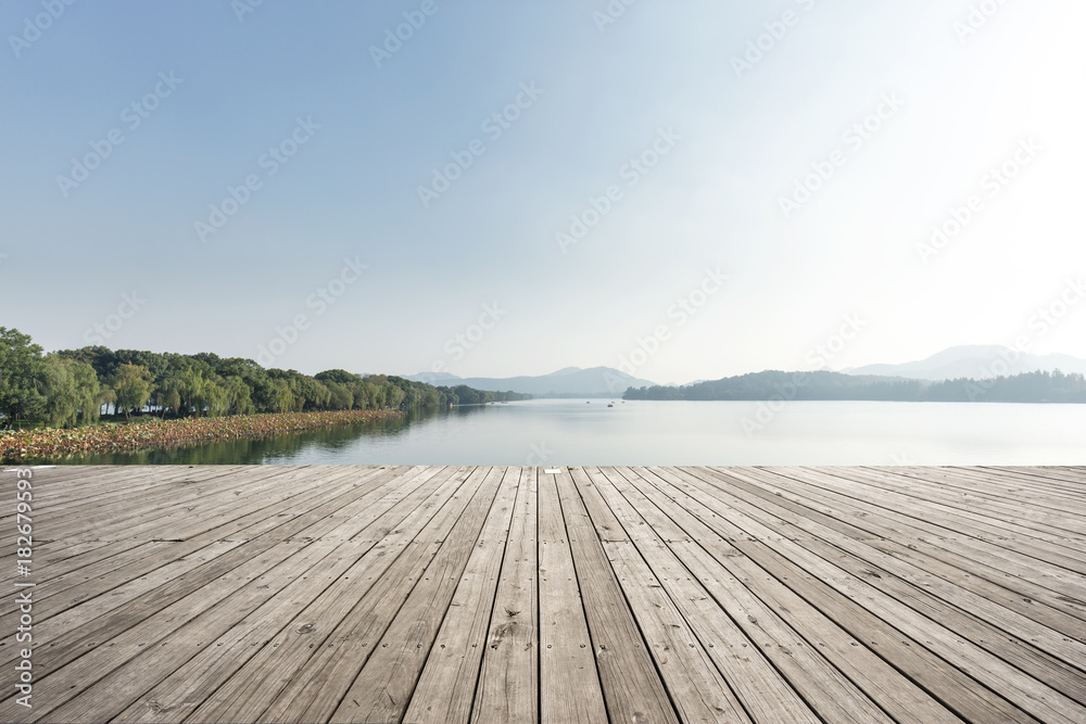 empty wooden floor with beautiful lake in blue sky