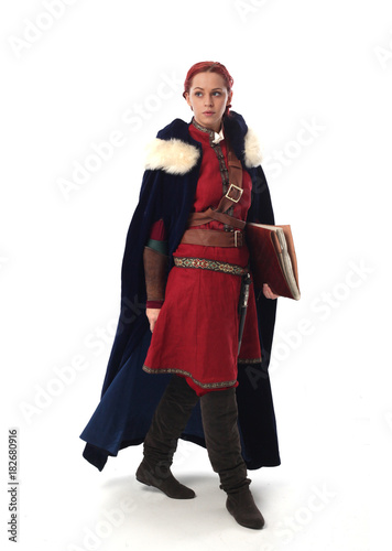 portrait of a red haired girl wearing medieval warrior outfit, studio background.