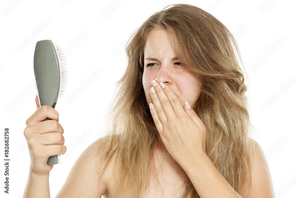 disgusted blonde with messy hair looking in hairbrush disgusted blonde with messy hair looking in hairbrush
