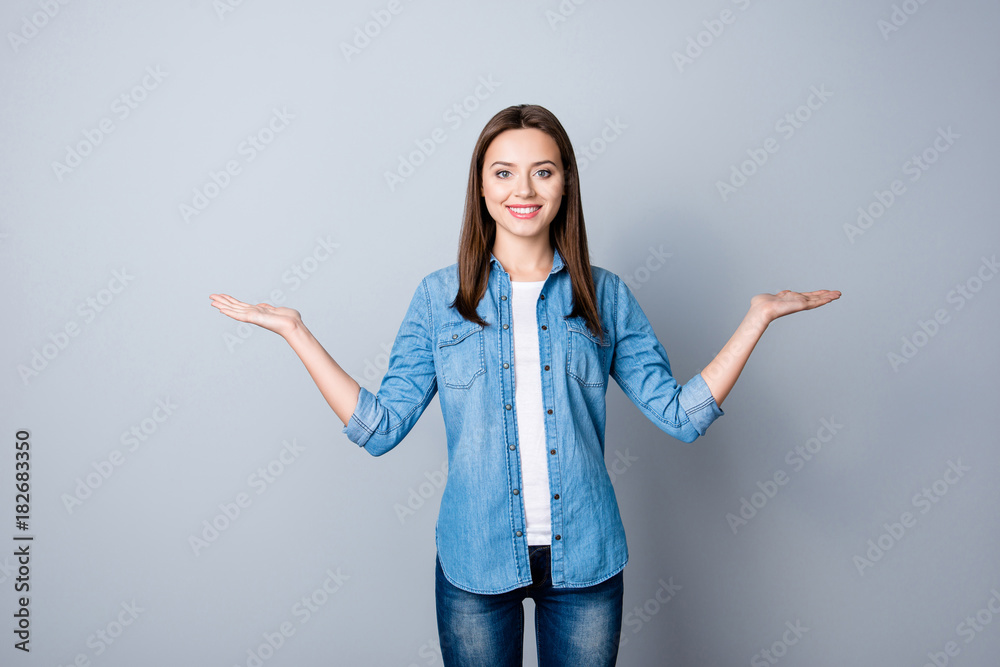 Portrait of successful cheerful cute young woman presenting something, showing copy space on her palm in two sides, looking at camera, standing over grey background Portrait of successful cheerful cute young woman presenting something, showing copy space on her palm in two sides, looking at camera, standing over grey background