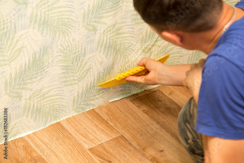 Man glues the wallpaper to the wall in the house