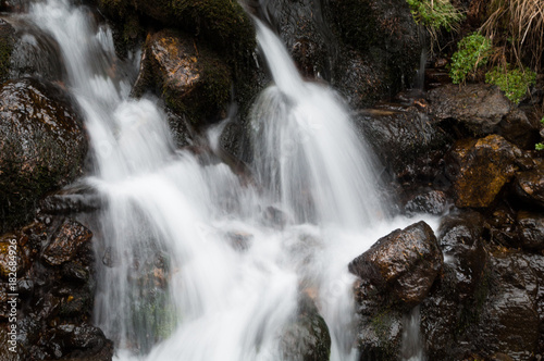 A small alpine stream rushing down the side of a mountain  long exposure 