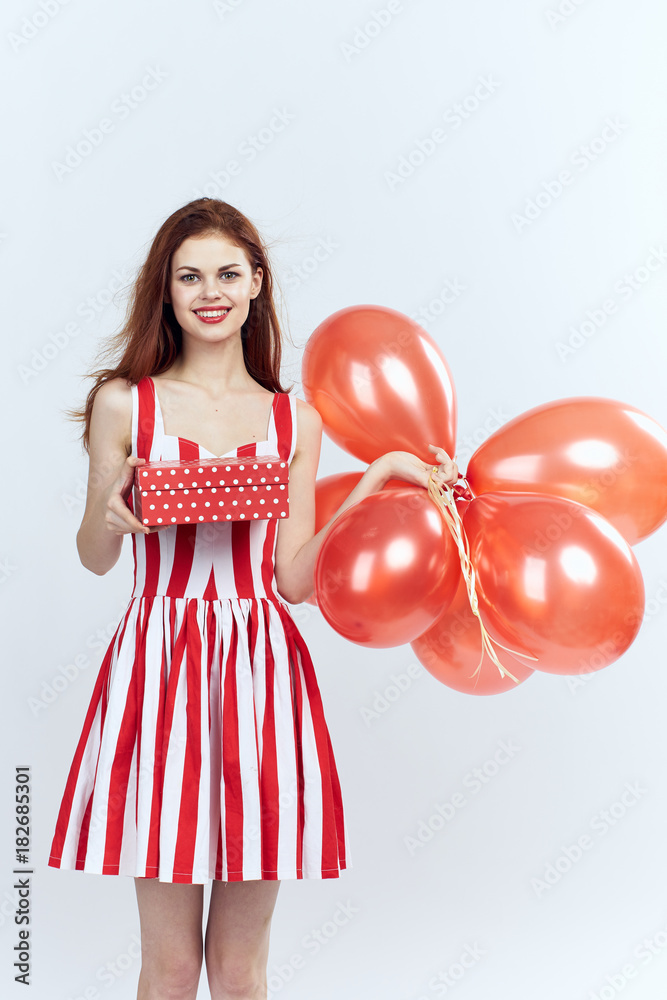 beautiful woman holds in hands a balloons and a gift, a light background beautiful woman holds in hands a balloons and a gift, a light background