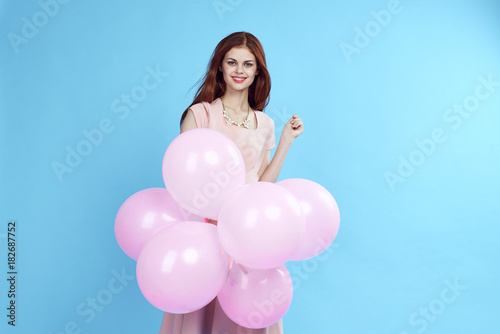 beautiful woman smiling and holding in her hand lots of balloons, light blue background, free space for copy