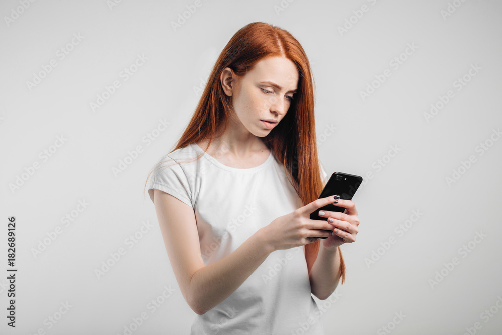 redhead girl with clean freckles skin using smartphone