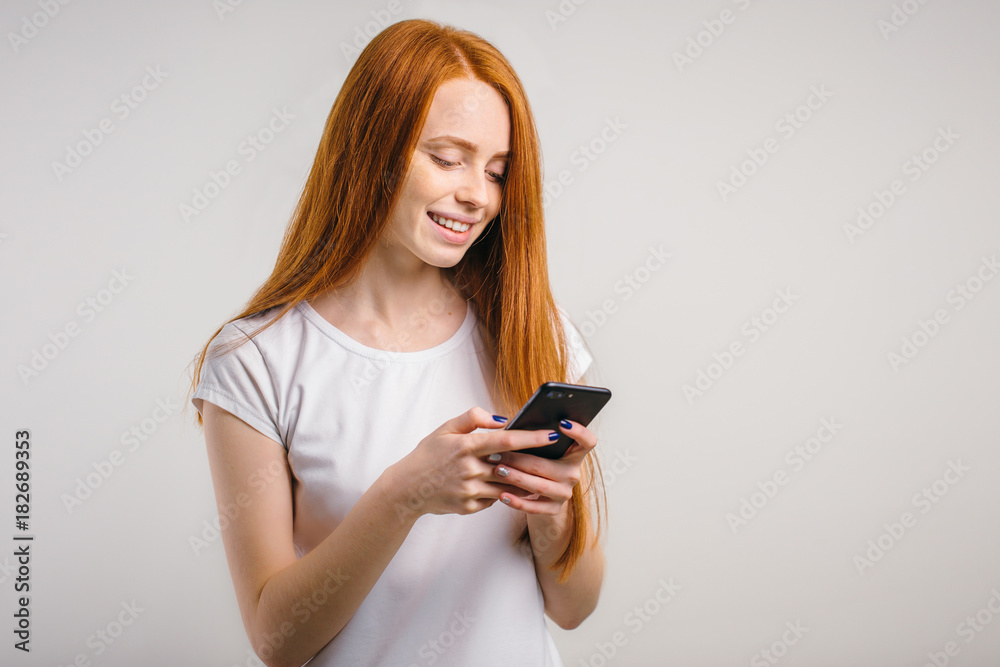 redhead girl with clean freckles skin using smartphone and texting and smile redhead girl with clean freckles skin using smartphone and texting and smile