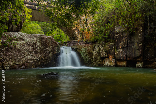 Rainforest waterfall under a road bridge.