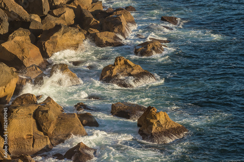Waves breaking against headland rocks.