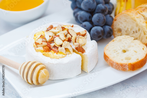 Brie cheese (camembert) with honey, nuts, baguette and fruit