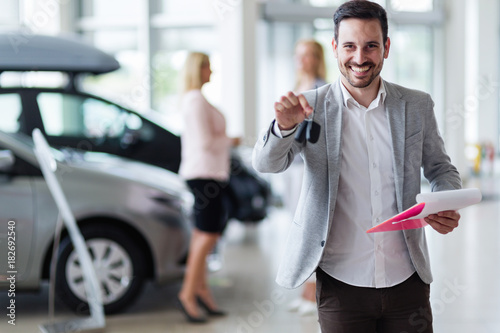 Canvas Print Handsome salesman at car dealership selling vehichles