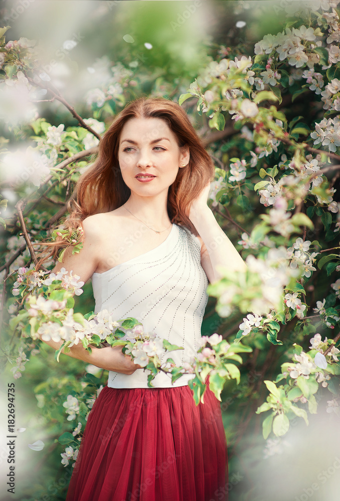 Young beautiful blonde woman in blooming garden