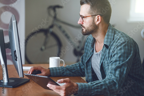 concentrated man with digital tablet and computer at table