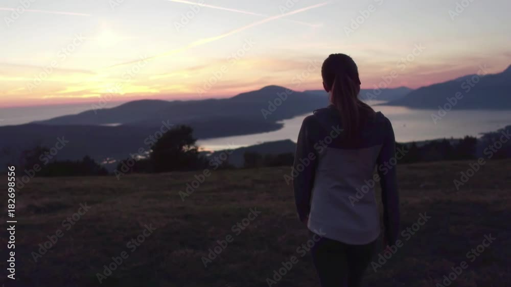 young woman walking at sunset on mountain peak young woman walking at sunset on mountain peak