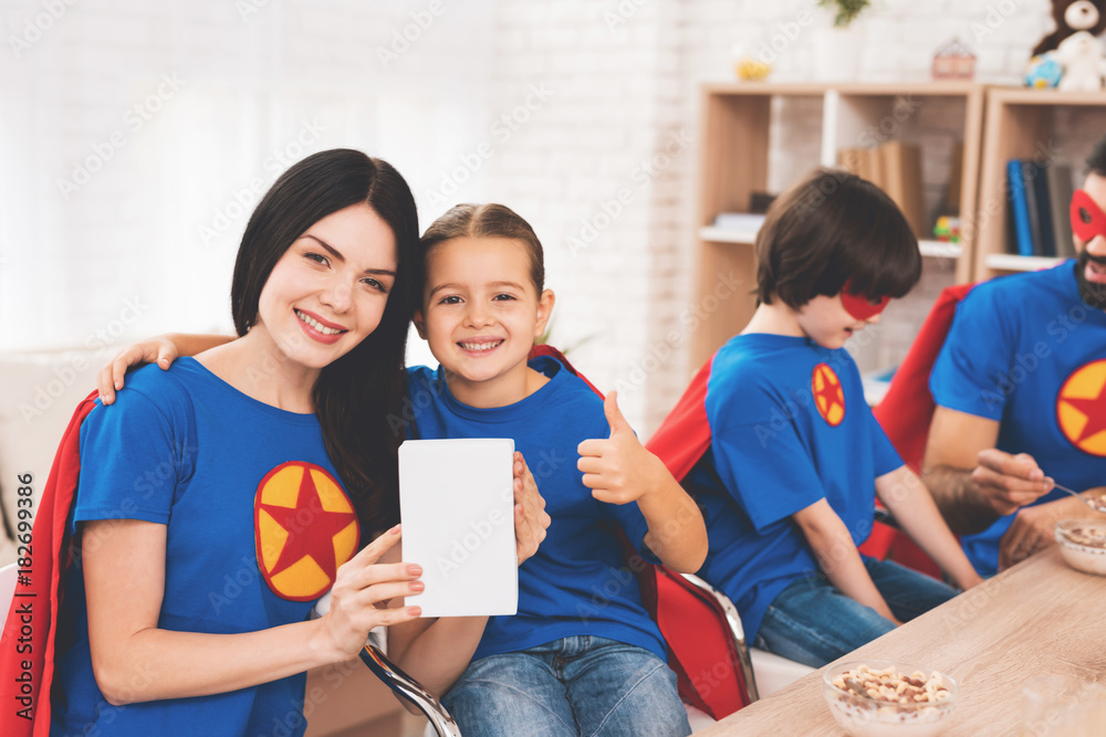 Young family in red and blue suits of superheroes. Their faces in masks and they are in raincoats. Young family in red and blue suits of superheroes. Their faces in masks and they are in raincoats.