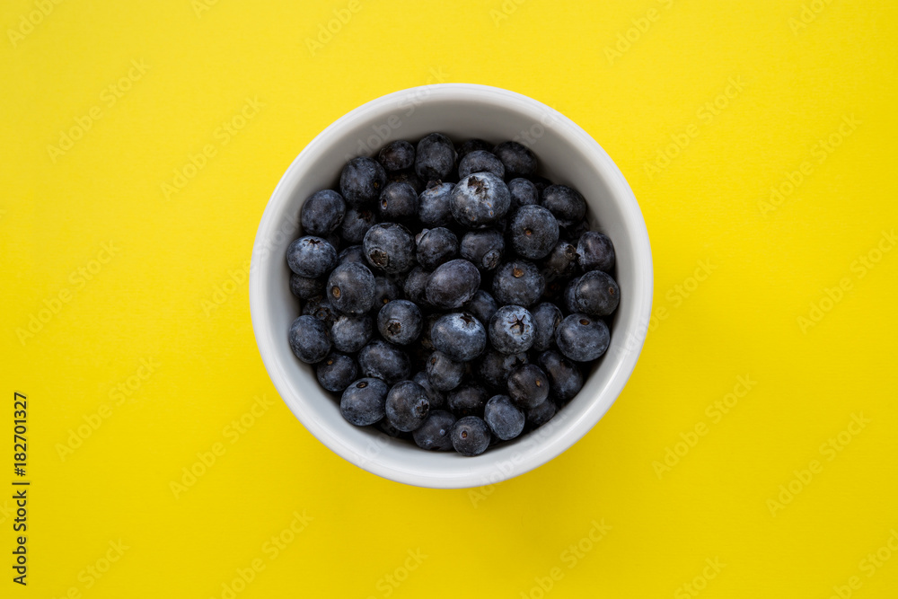 Bowl of blueberries on yellow background Bowl of blueberries on yellow background