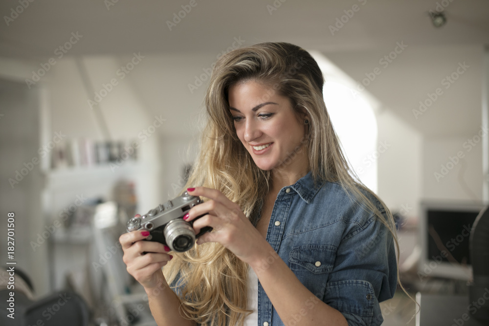 Indoor smiling lifestyle portrait of pretty young woman with camera Indoor smiling lifestyle portrait of pretty young woman with camera
