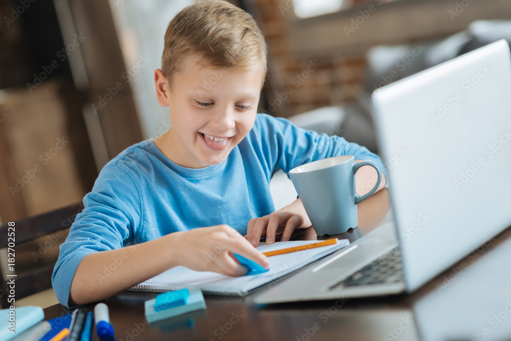 Creative task. Positive nice smart boy sitting at the table and using a highlighter while doing a creative task Creative task. Positive nice smart boy sitting at the table and using a highlighter while doing a creative task