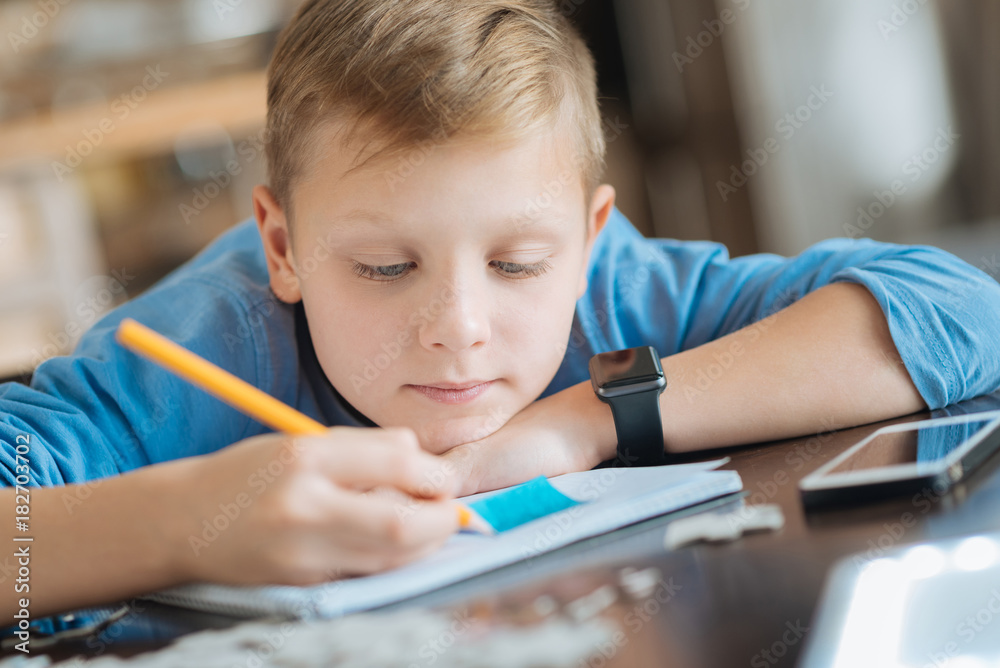 Being tired. Serious pleasant young looking at his copybook and holing a pencil while feeling tired Being tired. Serious pleasant young looking at his copybook and holing a pencil while feeling tired