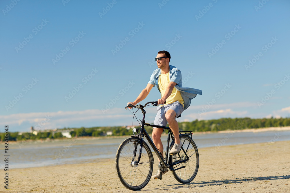 happy man riding bicycle along summer beach happy man riding bicycle along summer beach