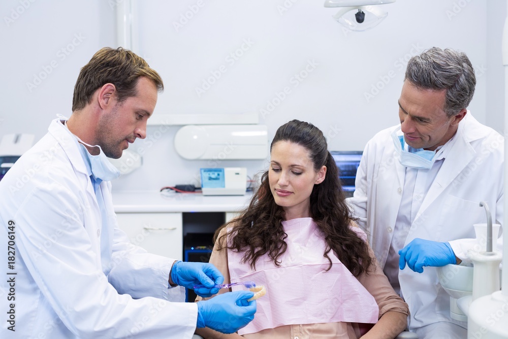 Dentist showing model teeth to patient Dentist showing model teeth to patient