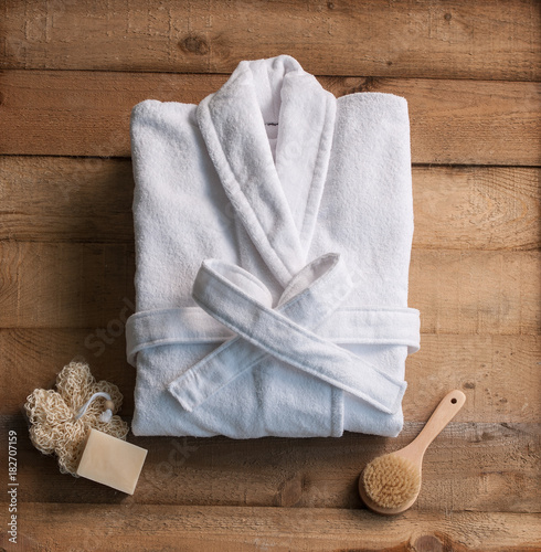 bathrobe bath soap and loofah brush behind wooden table wooden backgorund photo